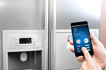 Man uses his smartphone to set up the fridge © Daniel Krasoń