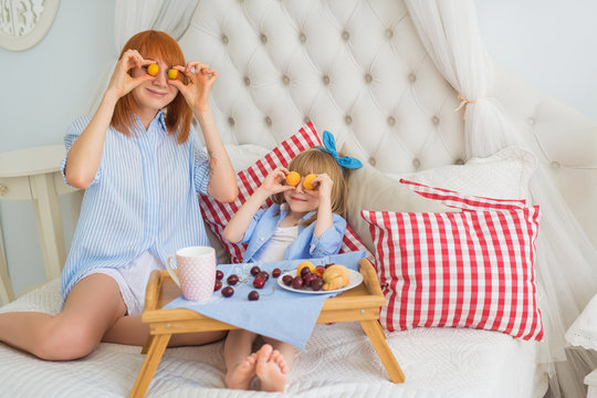 Mother and little daughter fun at breakfast on a bed