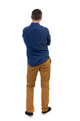 Back view of man . Standing young guy. Rear view people collection.  backside view of person.  Isolated over white background.a man in a blue shirt with the sleeves rolled up, standing with her hands