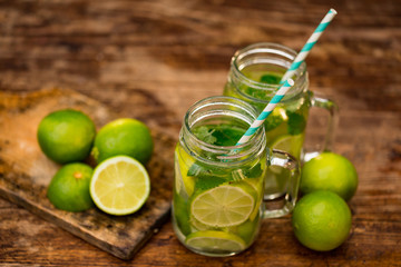 Fresh drink lemonade mojito in mason jar on wooden background.. Mojitos with mint leaves, lime and ice. View from above.
