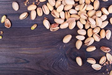 Salted pistachios on dark wooden background. Top view with copyspace