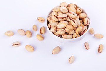 Salted pistachios in a bowl on white background. Space for text
