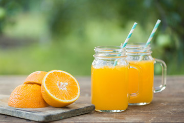 Fresh orange juice and orange sliced ripe on wooden table. Green background.