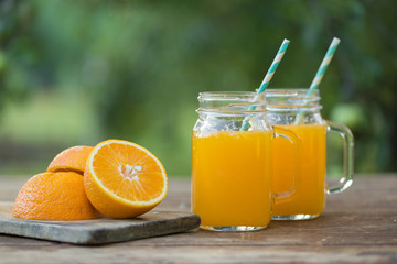 Fresh orange juice and orange sliced ripe on wooden table. Green background.