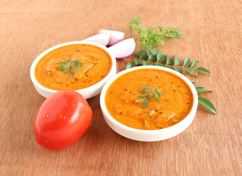 Indian food tomato curry, which is a healthy, traditional and popular side dish for items like chapati and rice, in two bowls.