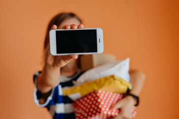 Closeup excited young woman holding present box using smartphone, light red orange background