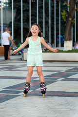 Little pretty girl on roller skates at a park