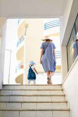 Fototapeta premium Back view of beautiful toddler girl walk with mother, stairs outdoors background, closeup view