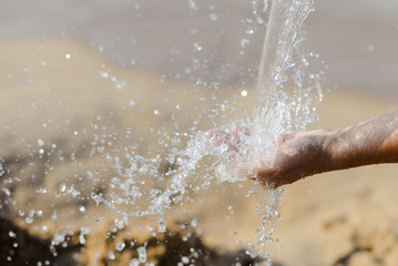 Close up of human hand catching water, ocean beach outdoors background