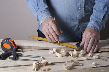 Carpenter working with plane on wooden background at Building Site. Joiner workplace