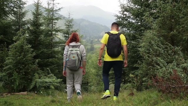 Couple Backpackers hiking on the path in mountains