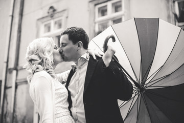 Groom kisses a bride turning down an umbrella