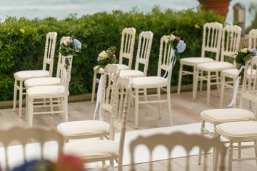 White chairs stand on the different sides of the path to wedding