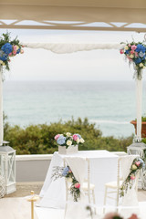 Wedding by the sea. White altar decorated with blue flowers