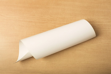 White paper on wood background, rolled up paper
