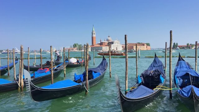 Parking gandolas on the Doge's palace embankment with the bell tower of the Saint Giorgio Maggiore church view.