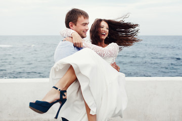 Groom whirls bride in blue shoes on the sea-front