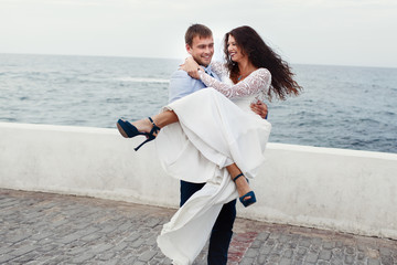 Bride in blue shoes smiles while groom holds her in his hands