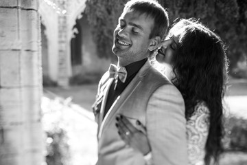 Black and white picture of a groom smiling while bride leans to