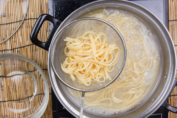 Spaghetti lifted on of cold water with colander