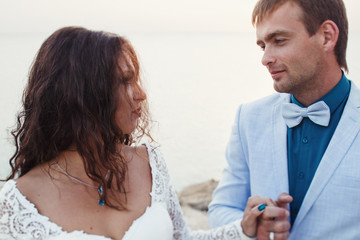 Woman with curly hair holds man's hand standing by the sea