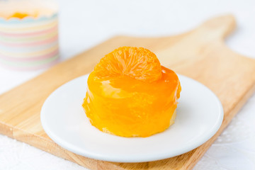 A piece of fluffy orange cake with orange glazed decoration.