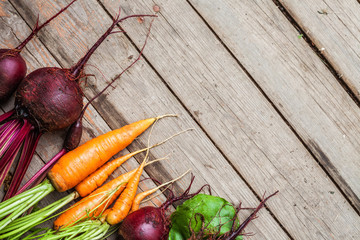 Fresh rustic natural vegetables carrots, beetroots on wooden background. Harvest still life top view with selective focus.