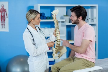 Physiotherapist explaining the spine model to patient