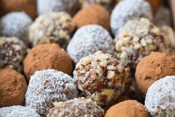 Hazelnut, cocoa, coconut and date homemade balls, lined up in rows.