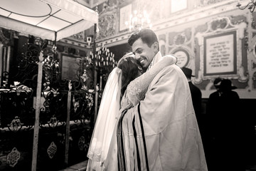 Black and white picture of smiling groom hugging bride in the sy