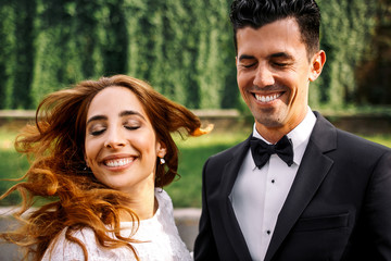 Groom laughs and closes his eyes while bride whirls her hair sta