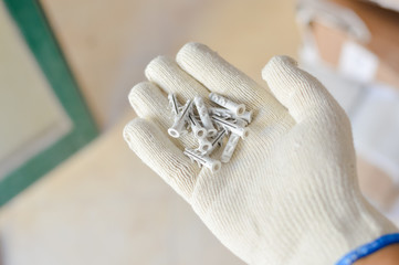 Person holding using wall plugs in hand, construction site background, dowels close up view