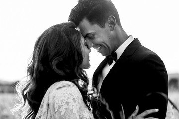 Smiling groom leans to bride's forehead standing with her in hig