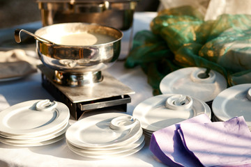 Steel bowl with sauce stands between white dinner plates