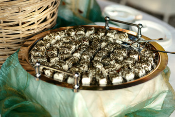 Cheese covered with dry greenery lies on the steel tray