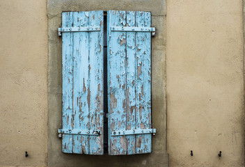 Old blue decaying peeling paint on window shutters in rural France