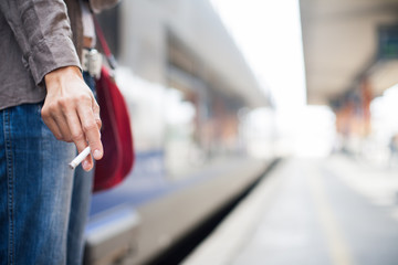 Obraz premium main de femme tenant une cigarette sur un quai de gare