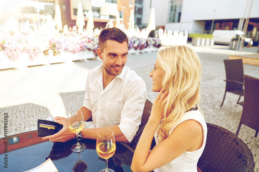 Poster happy couple with wallet paying bill at restaurant