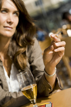 femme dans un café qui boit une bière en fumant une cigarette