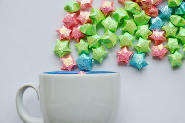 colorful star paper floating from coffee cup on white background