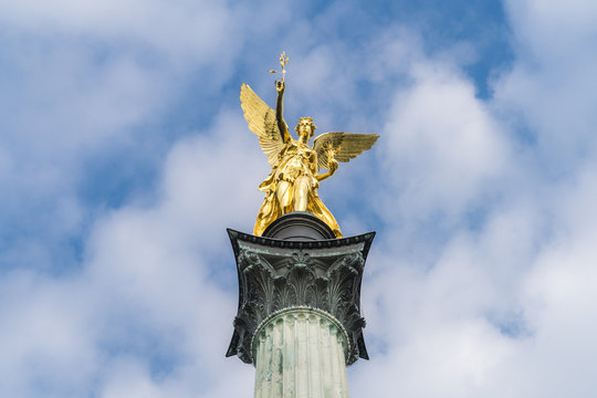 Goldener Friedensengel in München unter weiß-blauen Himmel