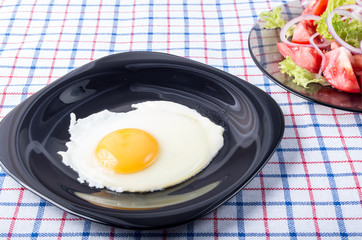 Small portion of the breakfast of fried egg and vegetable salad