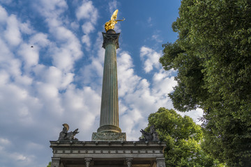Goldener Friedensengel in M&uuml;nchen unter wei&szlig;-blauen Himmel - gesehen von links