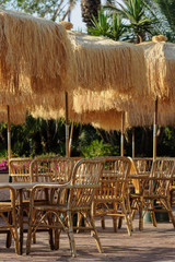 Tables and wicker chairs with straw sunshades in the restaurant