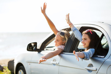 happy teenage girls or women in car at seaside