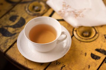 Taza de té sobre una mesa rústica de madera de color amarilla. Vista superior y de cerca
