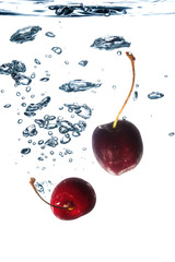 Fototapeta na wymiar Cherries splashing in water on white background