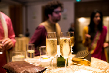Indian people talk on the background while cold champagne glasse