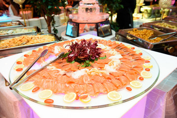 Slices of red fish and lemon lie on the large serving dish
