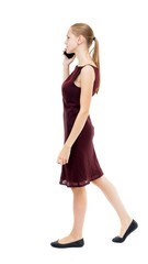a side view of a woman walking with a mobile phone. beautiful curly girl in motion.  backside view of person.  Rear view people collection. Isolated over white background.  A girl in a burgundy dress